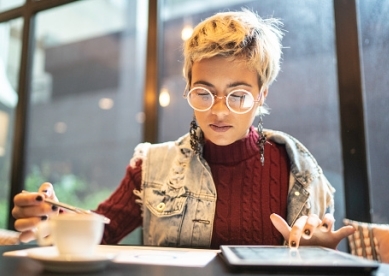 Young woman looking at digital investments on a tablet in cafe